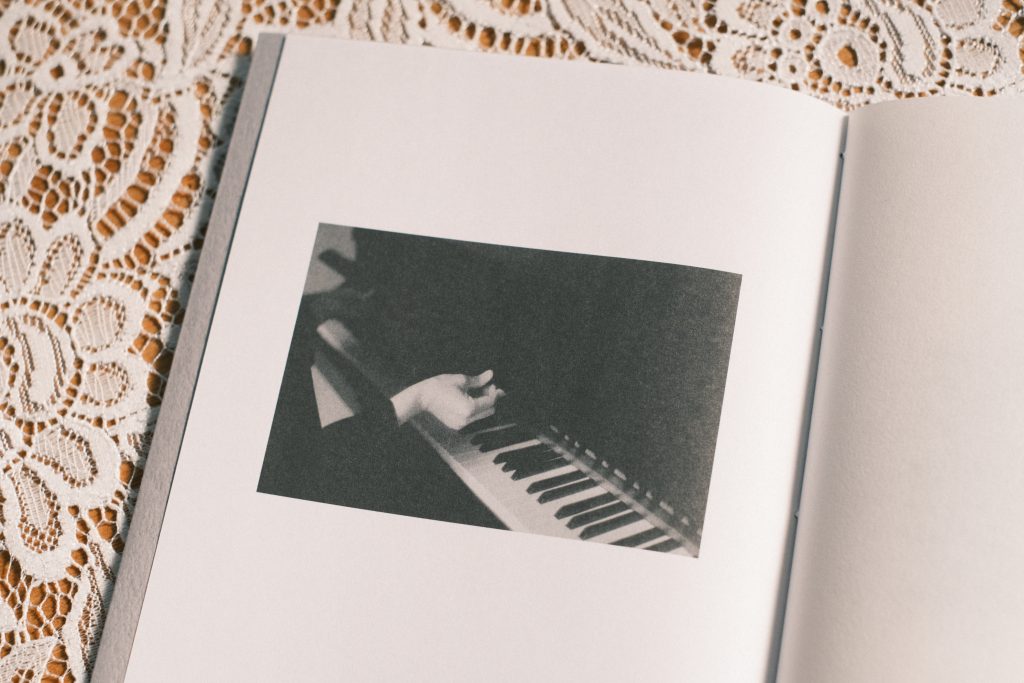 『Rêverie 日曜日の夢の始まり』のブックレットでピアノを弾く上柿さんの写真
