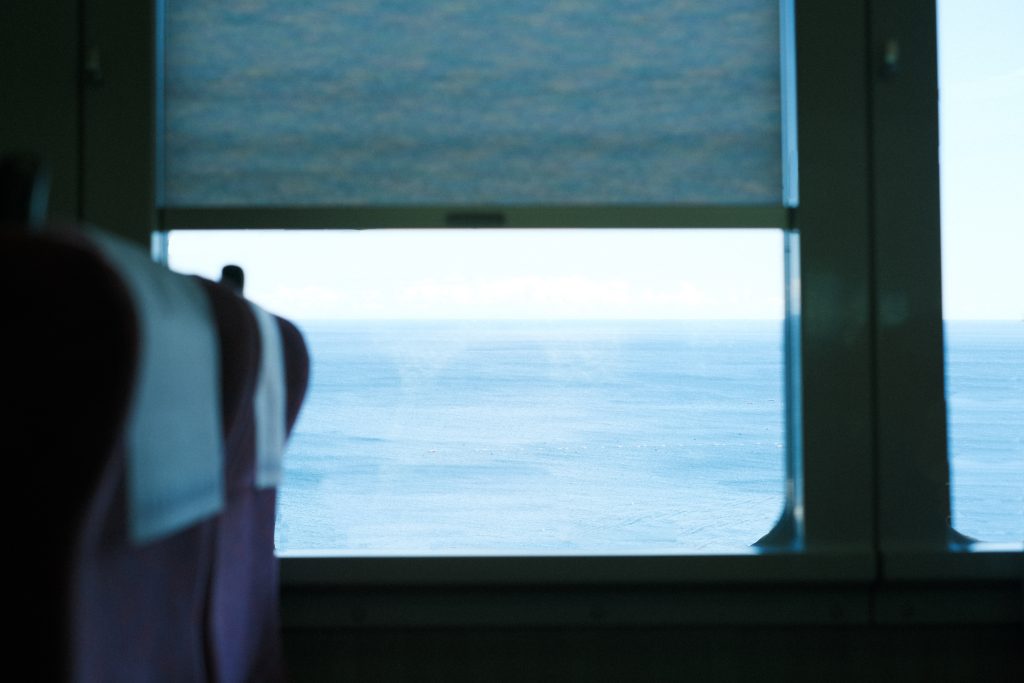 電車の窓越しに見る海の写真